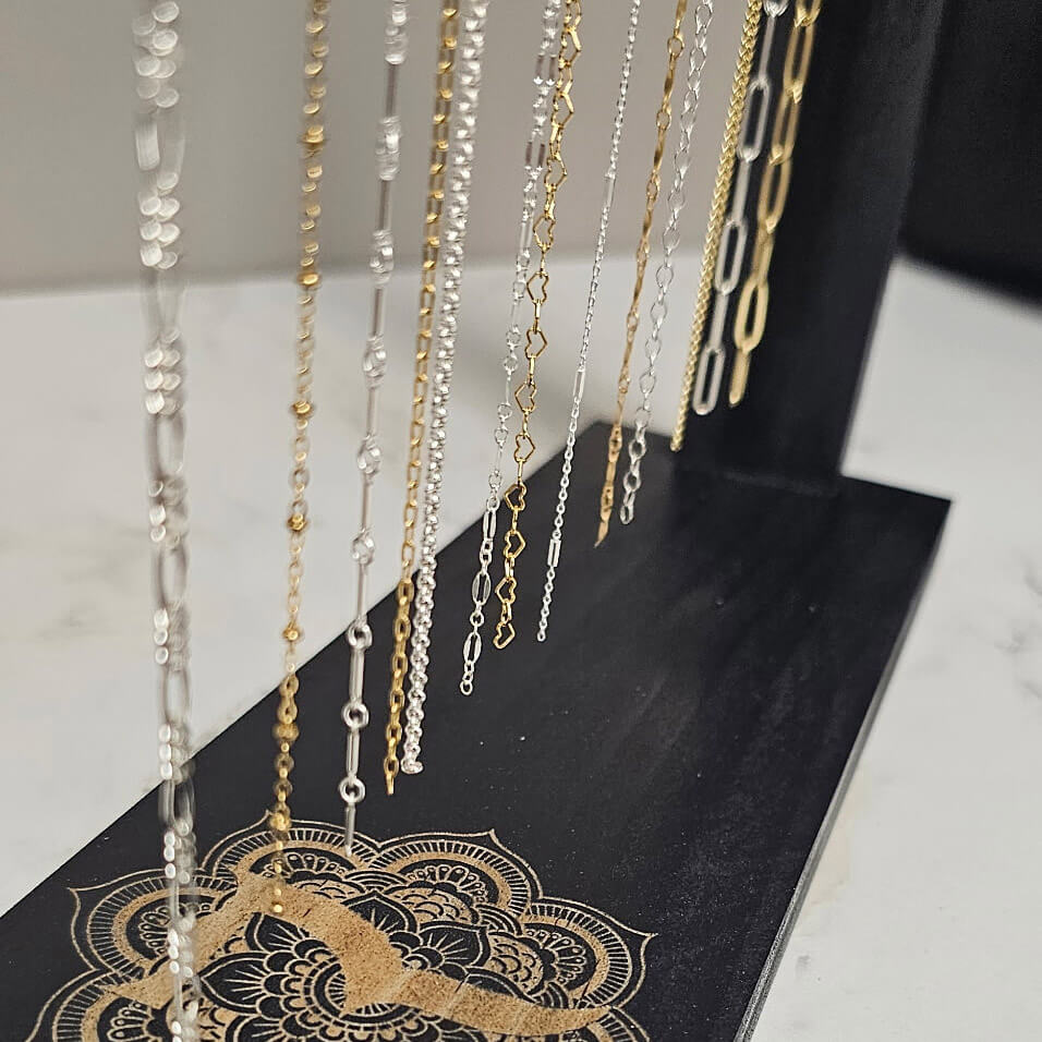 A Royal Pampering Permanent Jewelry rack showing a selection of gold and silver chains